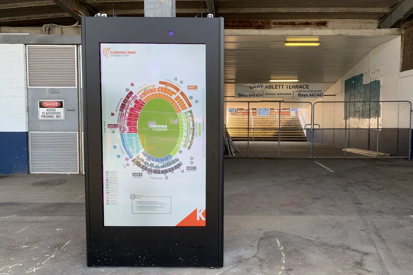 Digital wayfinding totem showing a venue map in a public concourse