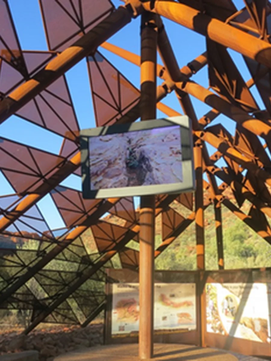 Commercial LCD display mounted under an open architectural canopy at a visitor centre
