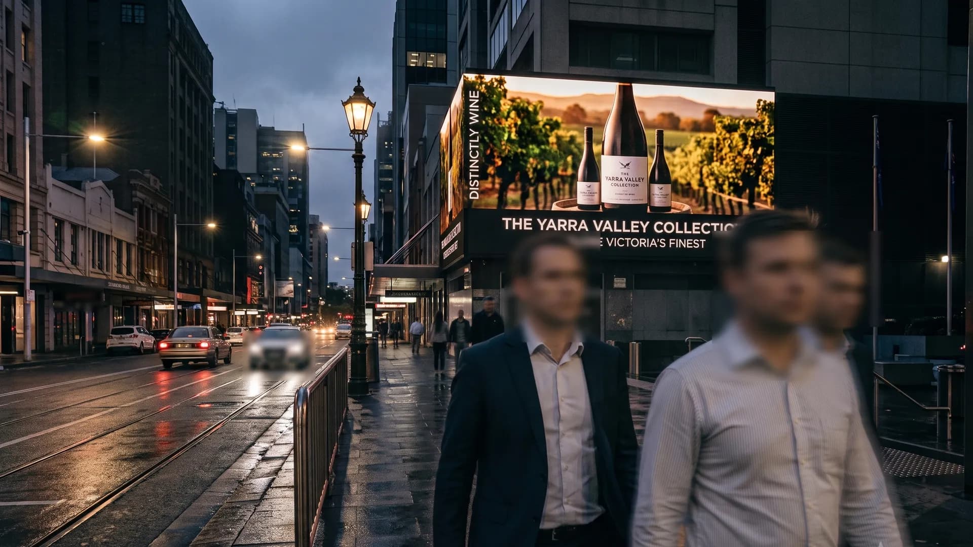 Large format digital screen above a city street at dusk with passing foot traffic